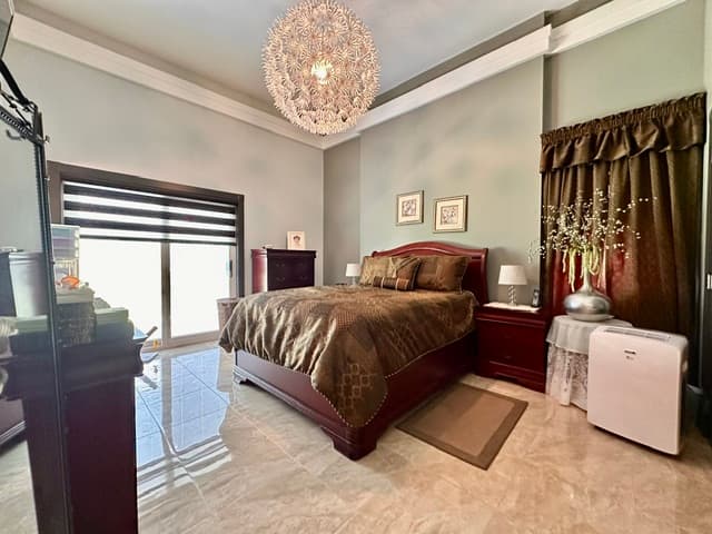 Bedroom with large bed, chandelier, and natural light